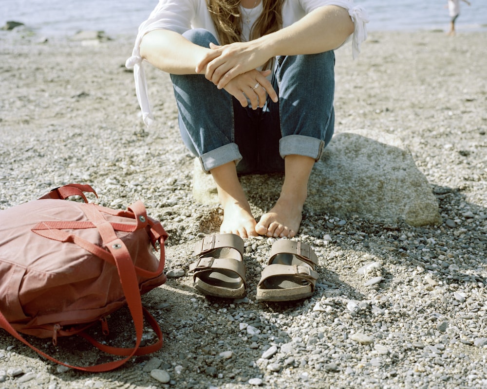 woman in blue denim shorts and brown leather sandals standing on gray rock during daytime