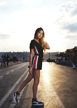 A confident man in sharp athletic wear standing against a moody urban backdrop at dusk.