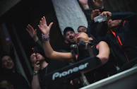 The DJ performing passionately on stage, with an intense expression and a sea of hands raised in the crowd.