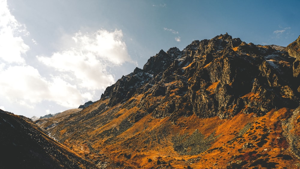 brown and gray rocky mountain under white clouds and blue sky during daytime