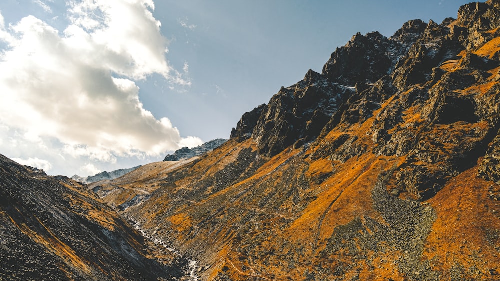 brown and green mountains under white clouds and blue sky during daytime