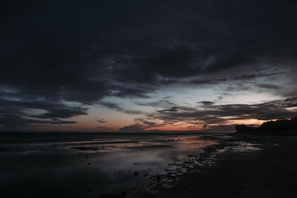 corpo de água sob o céu nublado durante o pôr do sol