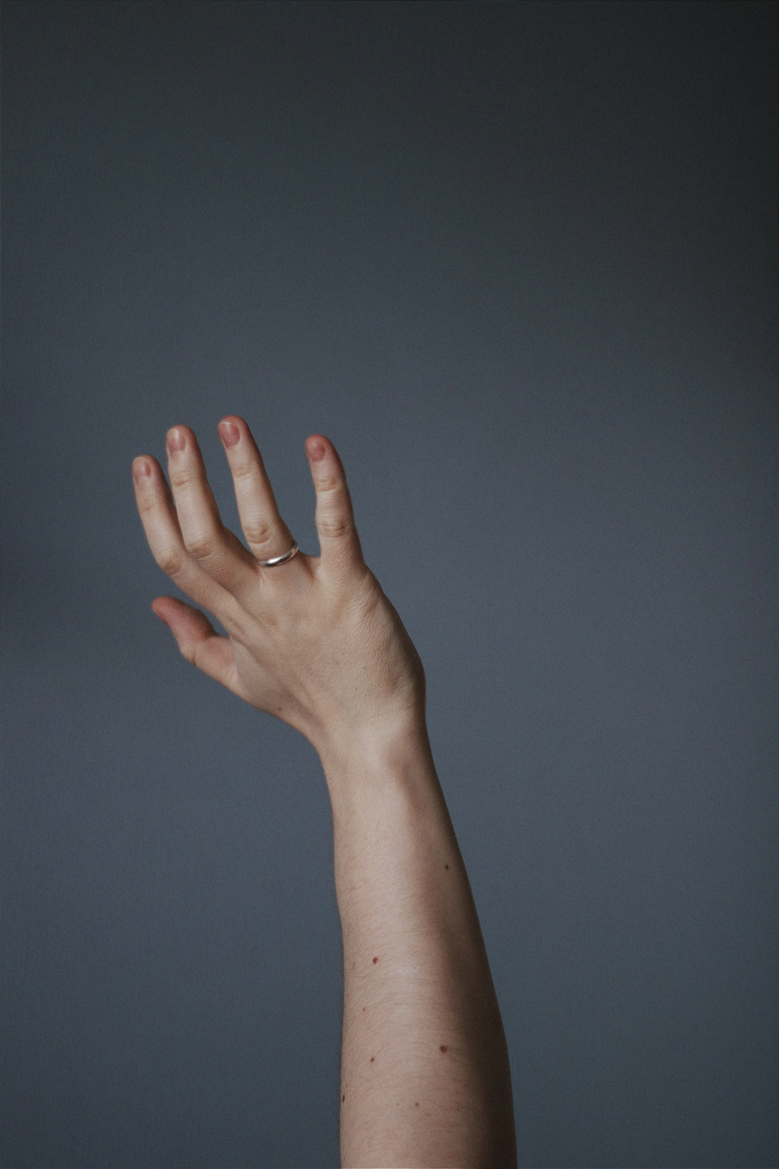 A gold ring on a hand beside delicate jewelry