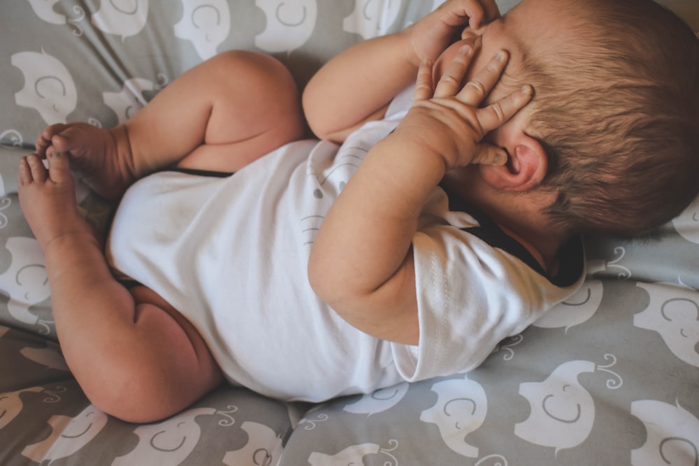 bambino in camicia bianca sdraiato sul letto