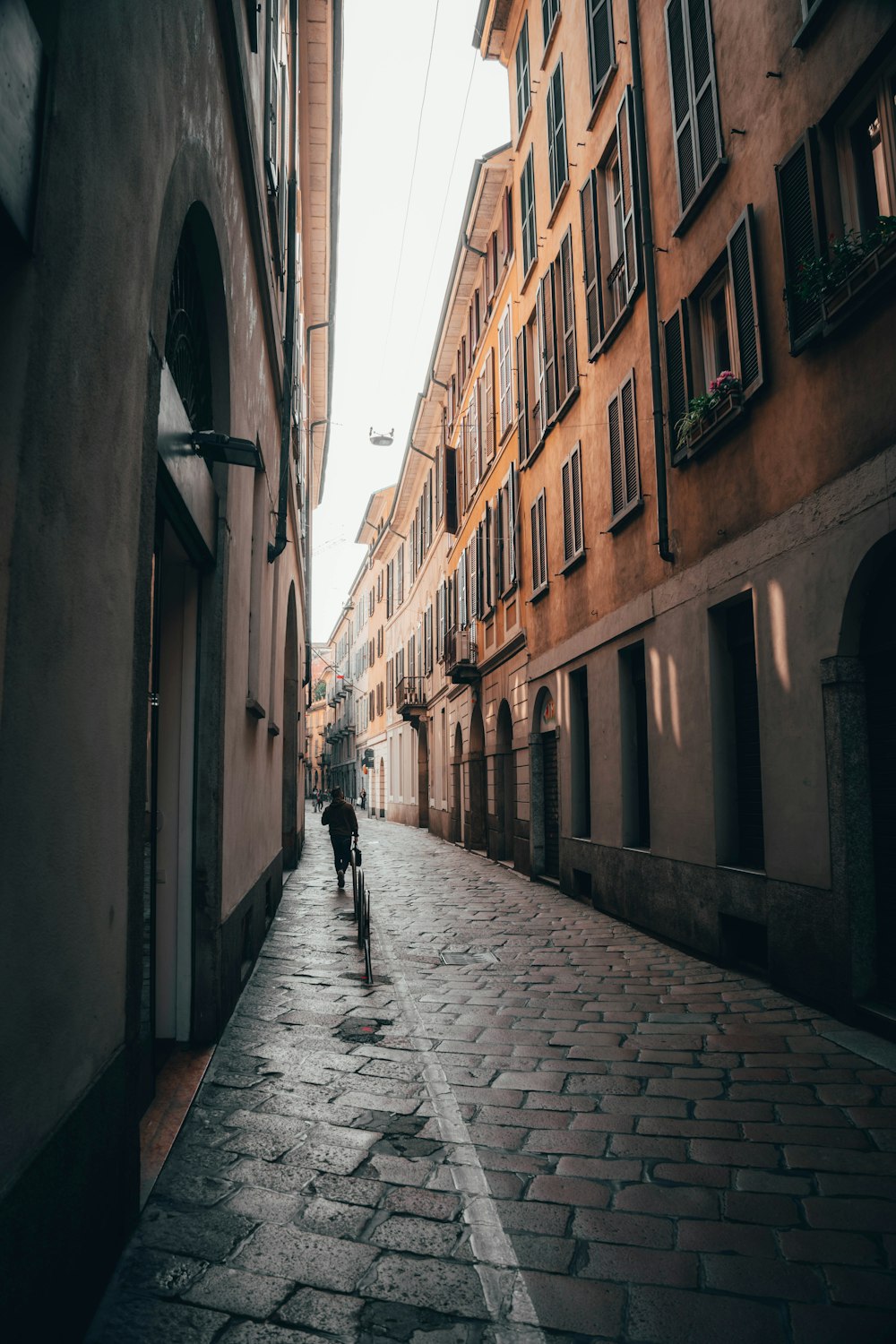 person walking on sidewalk between buildings during daytime