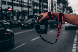 Close-up of hands holding a camera capturing a street scene