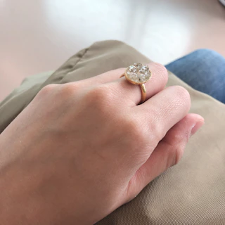 Close-up of a delicate gold ring with a sparkling gemstone resting on soft beige fabric.