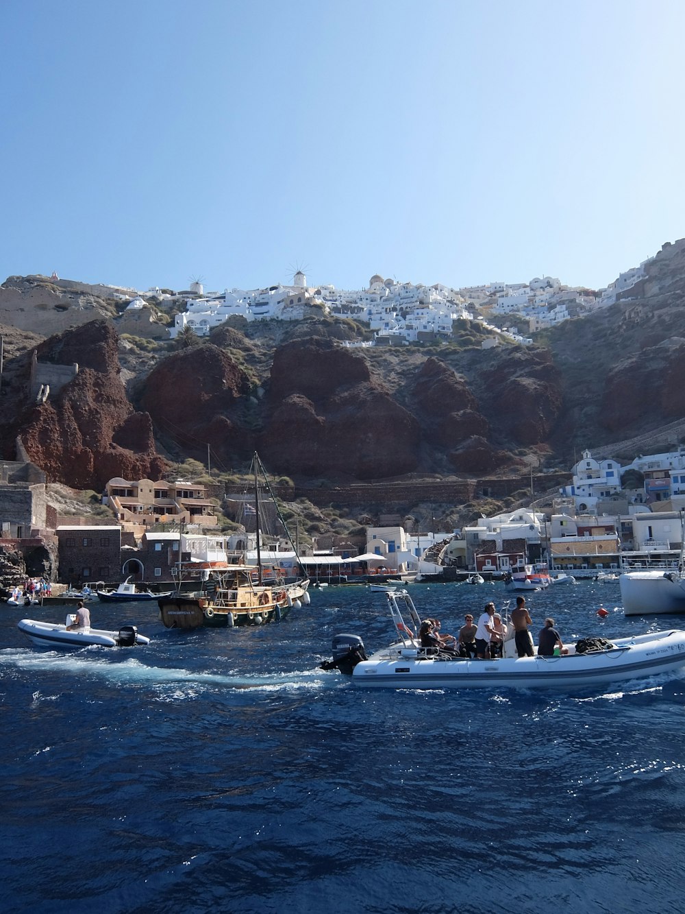 people riding on boat on sea near brown mountain during daytime