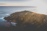 A panoramic view of the rugged Atlantic coastline with crashing waves under a golden sunset.