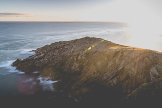 A rugged Atlantic coastline at sunrise with waves gently crashing against weathered rocks.