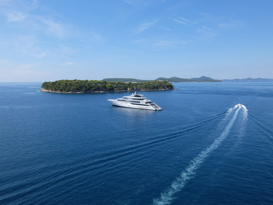A yacht passing a small wooded island in open sea.