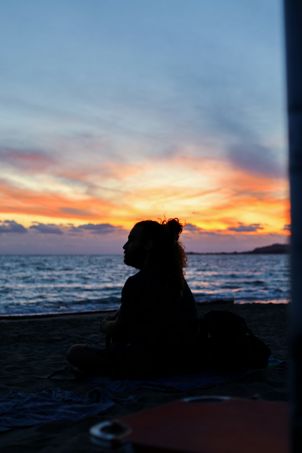 Silhouette eines Hundes, der während des Sonnenuntergangs an der Küste sitzt