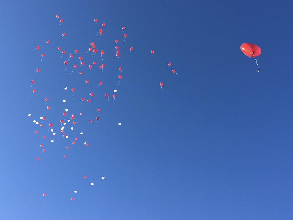 red balloon floating on blue sky during daytime