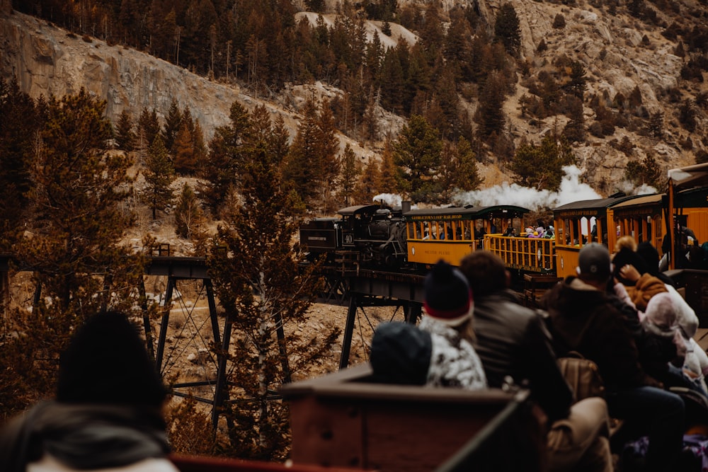 people sitting on bench near snow covered mountain during daytime