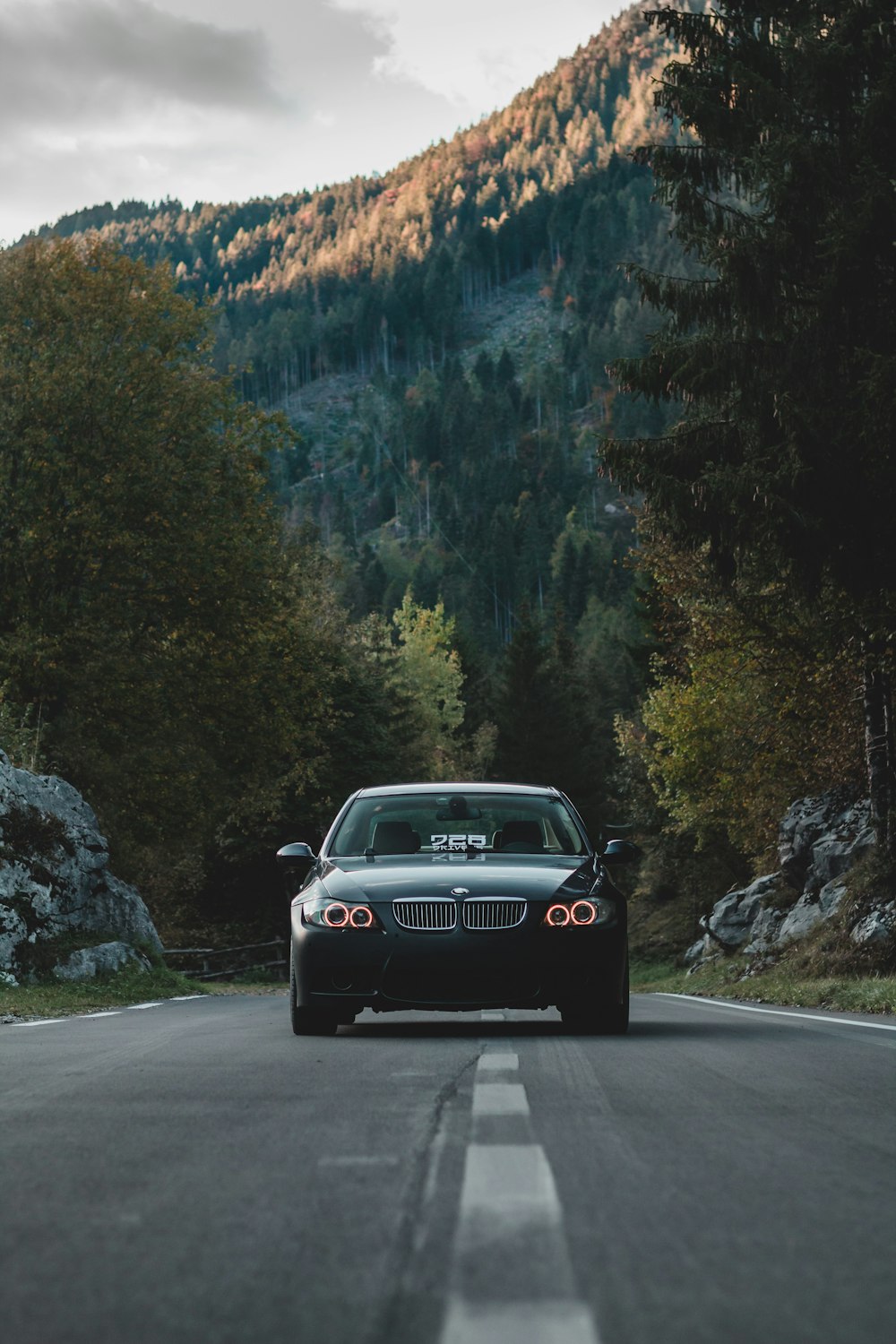 black porsche 911 on road near green trees and mountain during daytime