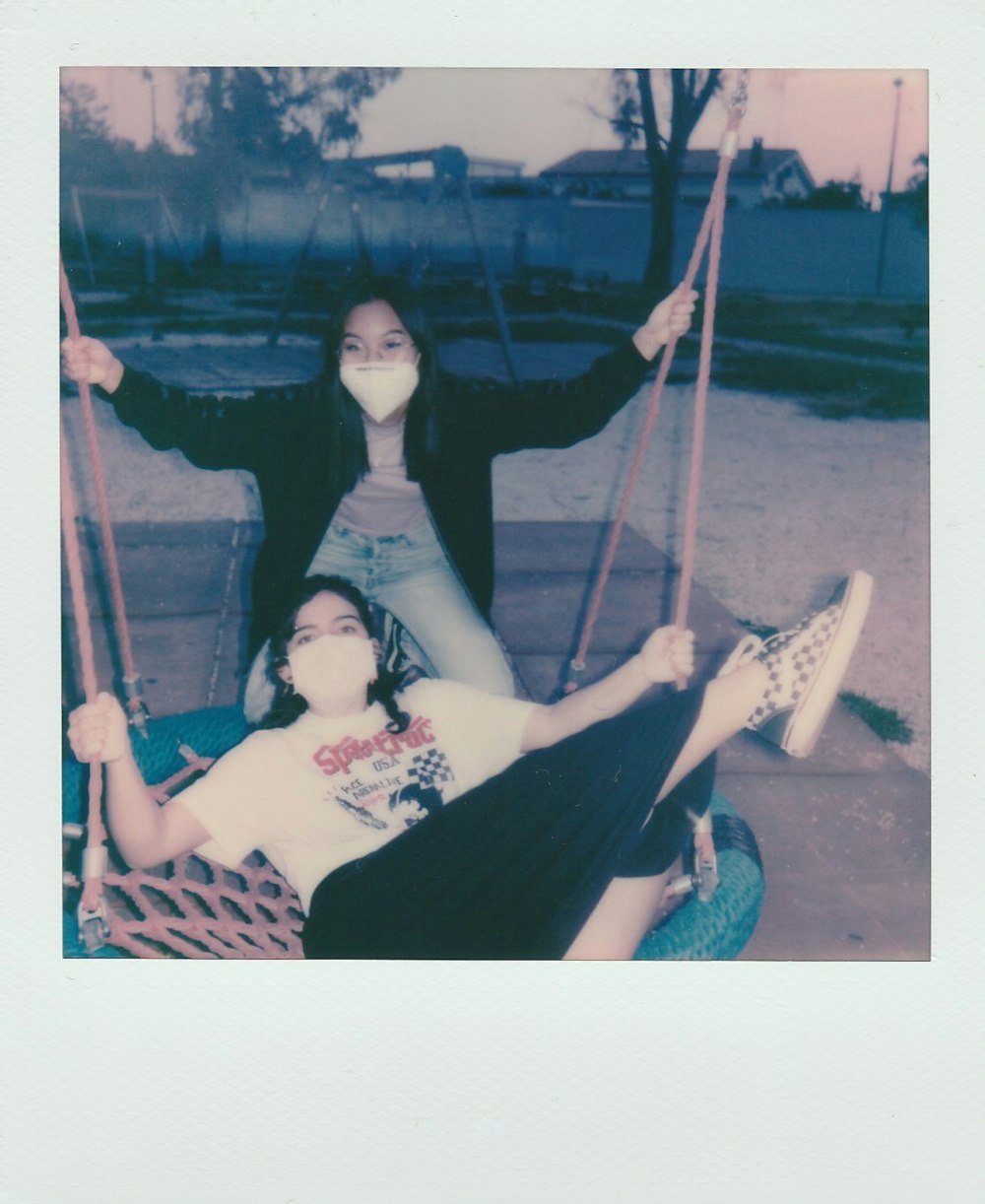 2 women in white and black dress on blue and white hammock