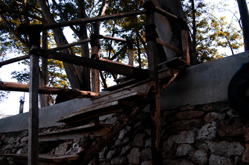 A rustic wooden staircase winding upward, surrounded by dark green walls and natural wood textures.