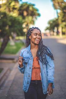 woman in blue denim jacket standing on sidewalk during daytime