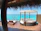 A couple relaxing on a turquoise-themed porch overlooking lush greenery by the sea.