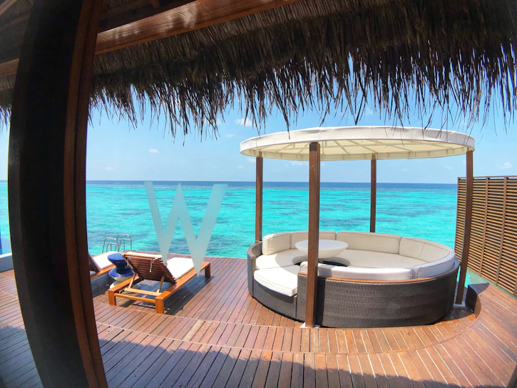 A sunlit terrace overlooking the turquoise sea with elegant outdoor furniture.