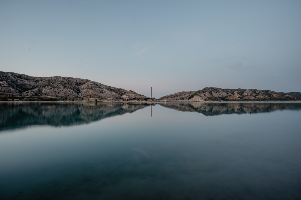 body of water near mountain during daytime