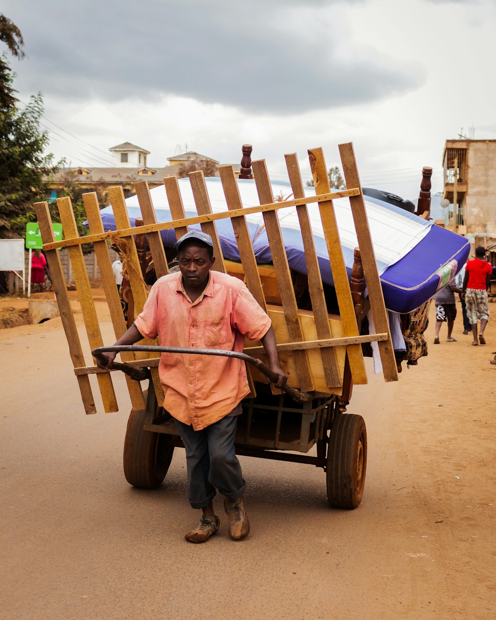 man in pink shirt sitting on blue and white wooden carriage during daytime