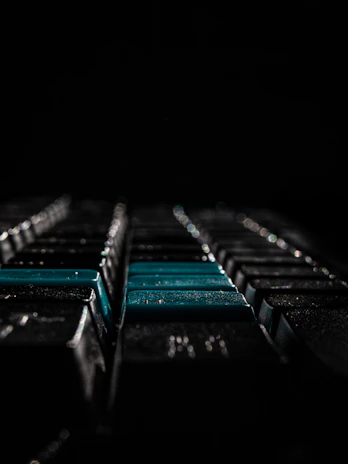 An artistic shot of a keyboard with typed jokes on screen, set against a dark, aesthetic background.