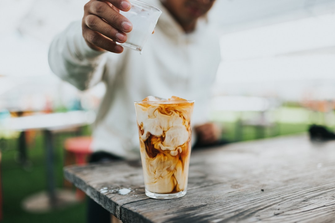 person holding clear drinking glass with ice cream