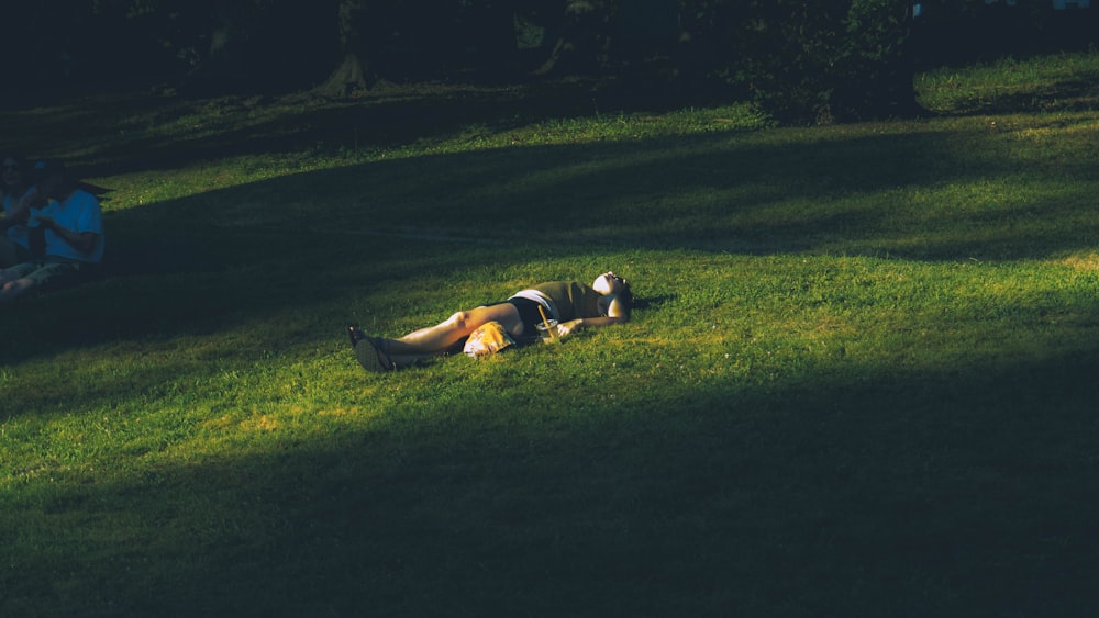 man lying on green grass field during daytime