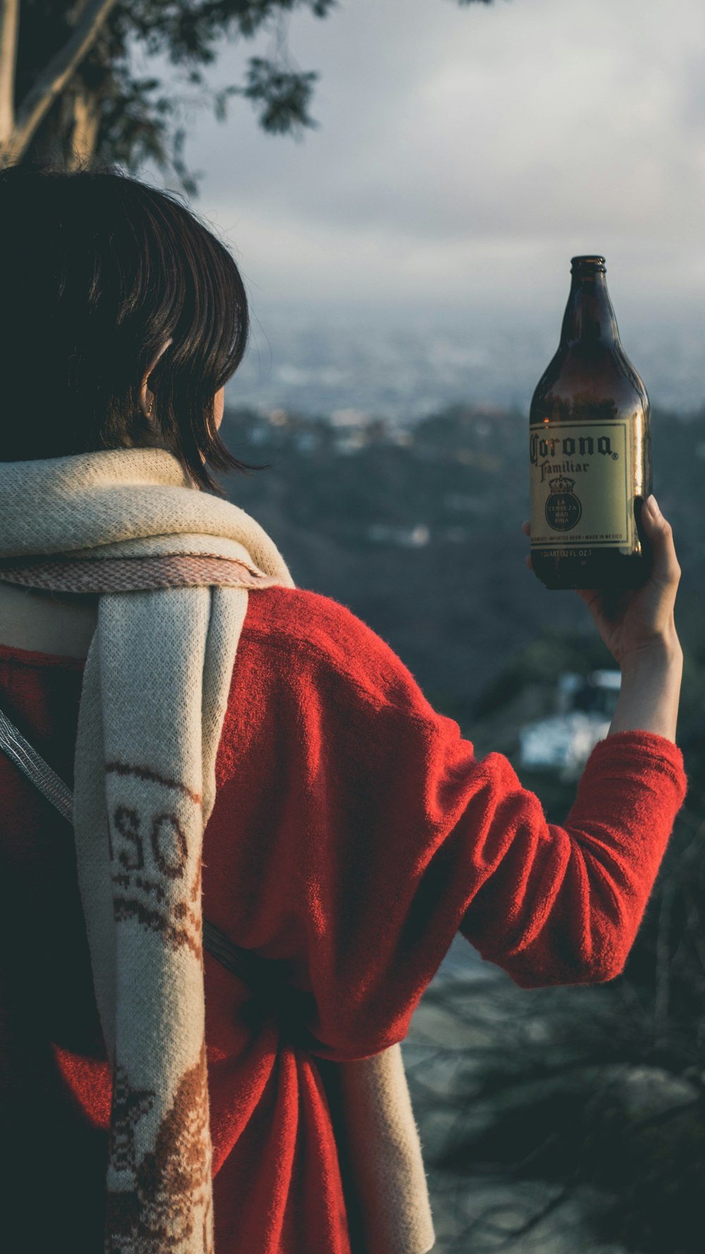 woman in red and white coat holding bottle