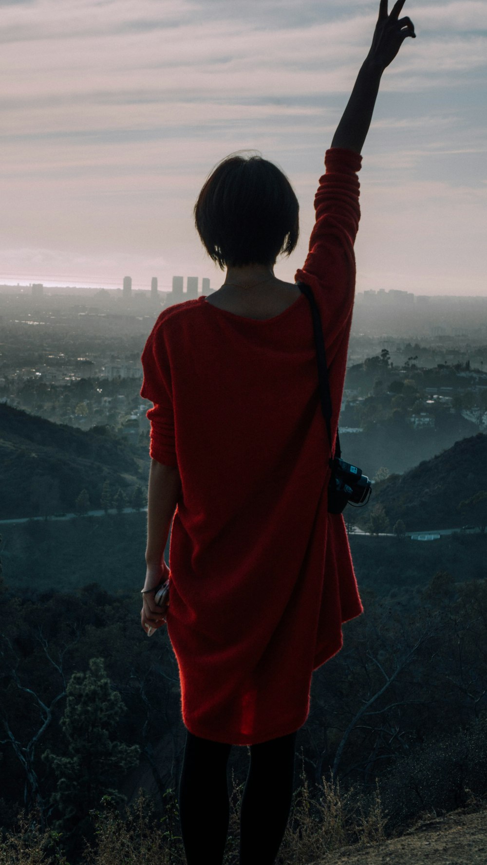 Frau im roten Hemd steht tagsüber auf dem Gipfel des Berges