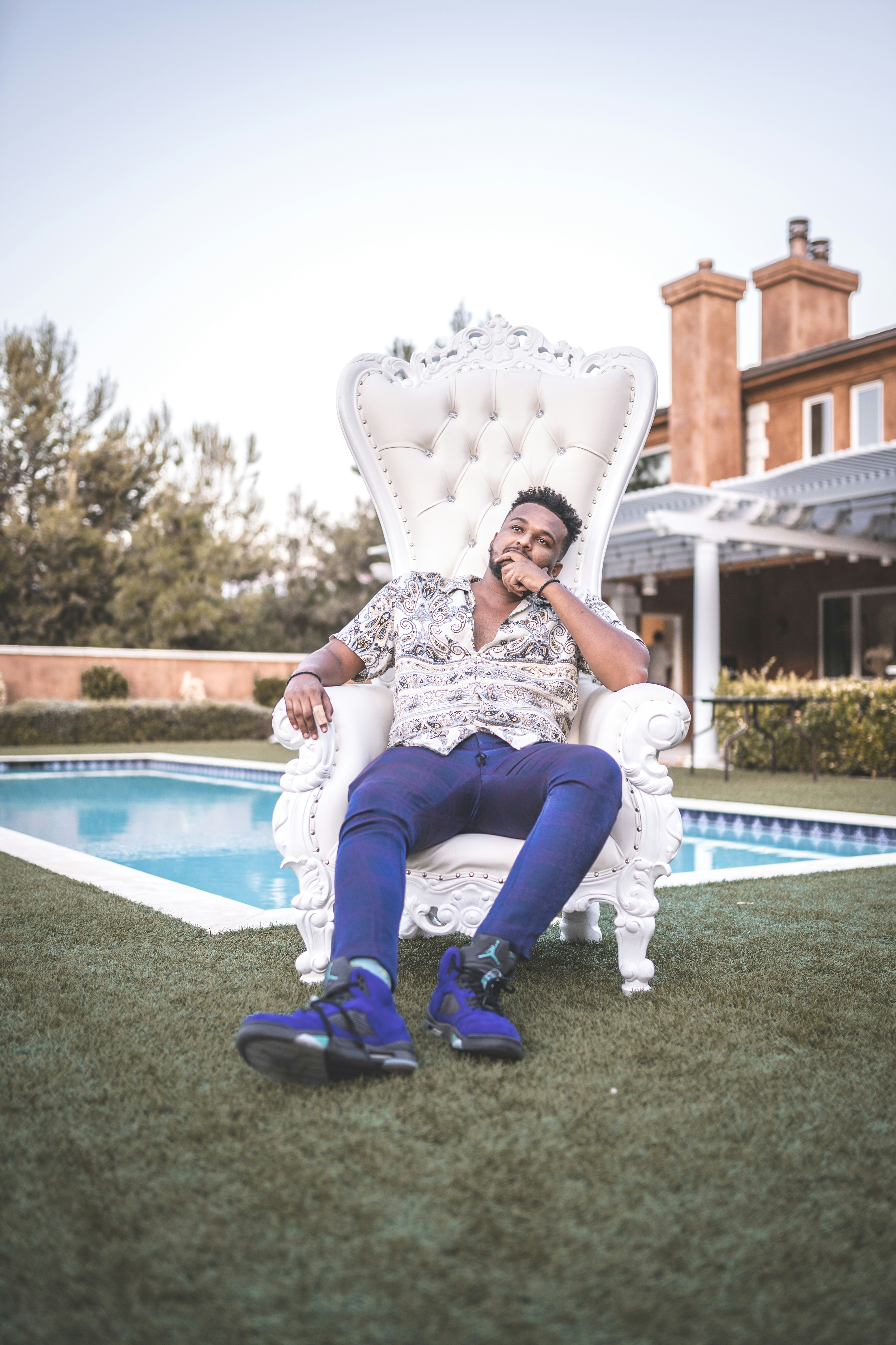 woman in white and black floral dress sitting on white and blue outdoor pool during daytime