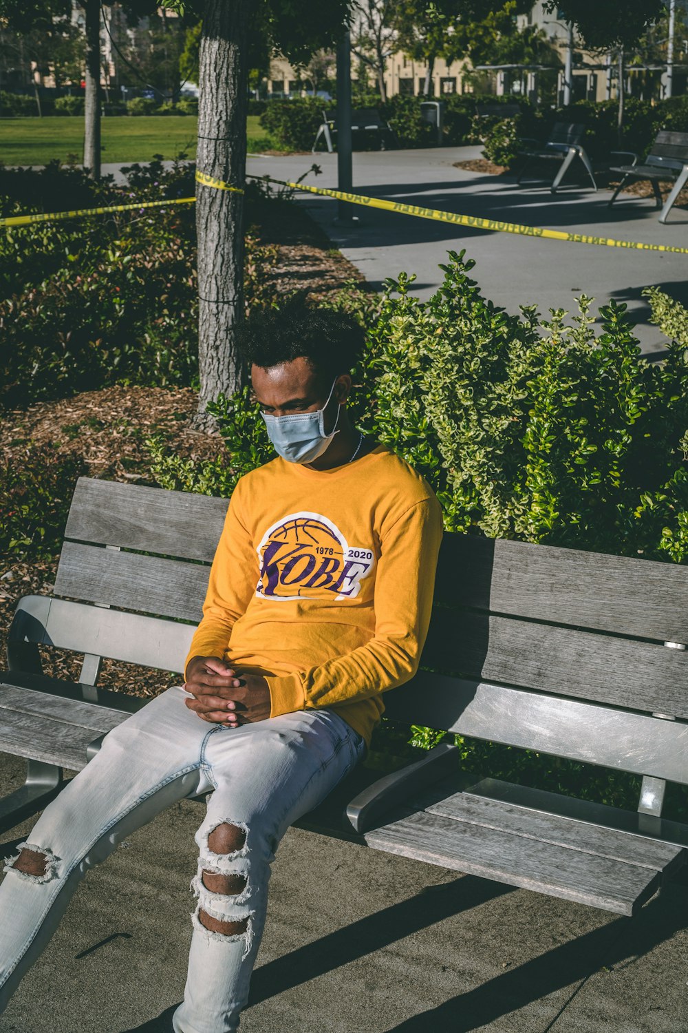 man in yellow and black hoodie sitting on brown wooden bench