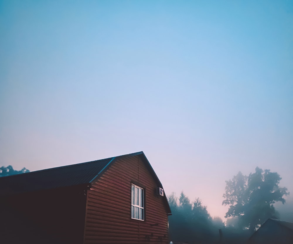 brown wooden house near green trees under white sky during daytime