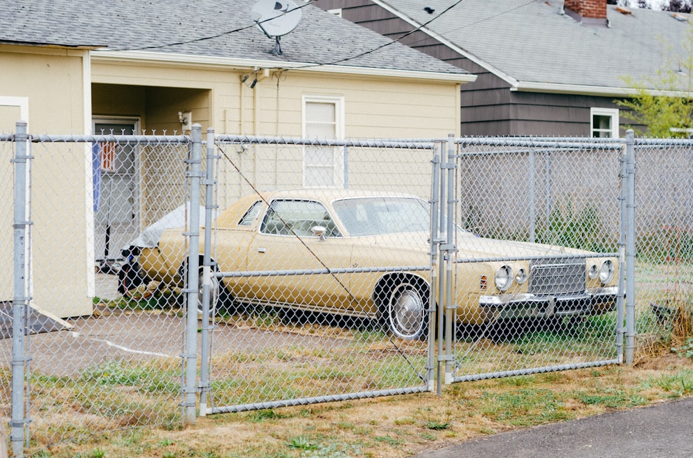 white and brown sedan parked beside white metal fence during daytime