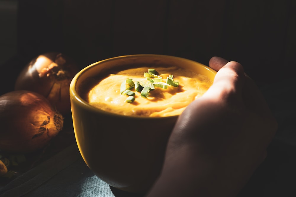 person holding black ceramic bowl with soup