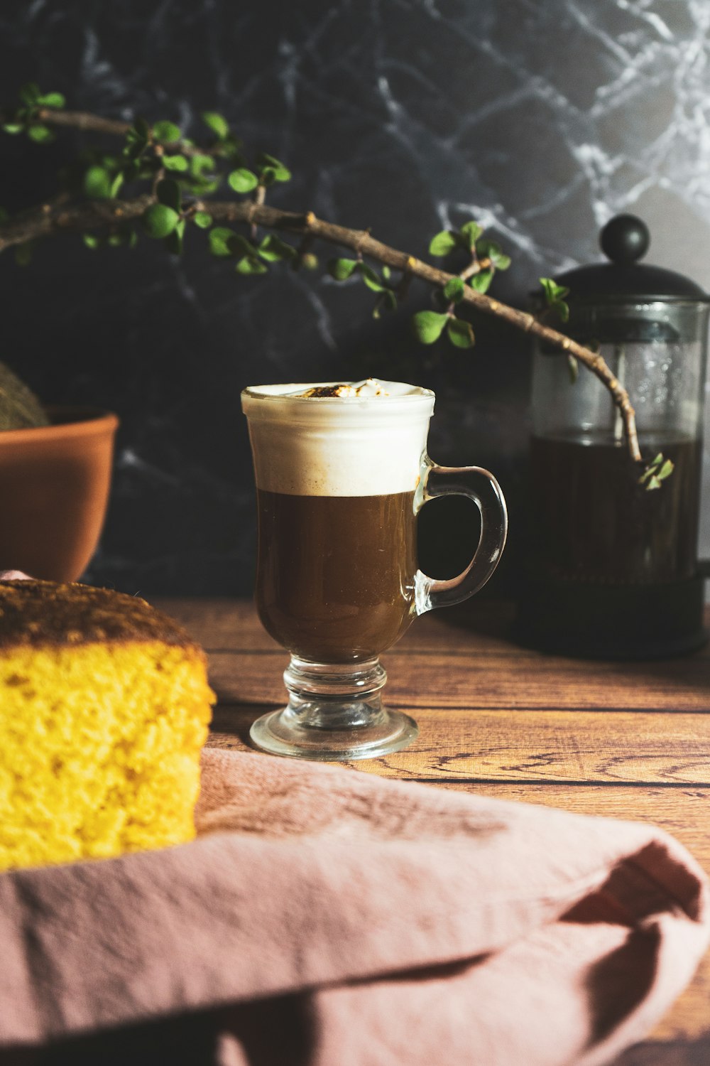 clear glass mug with brown liquid on brown wooden table