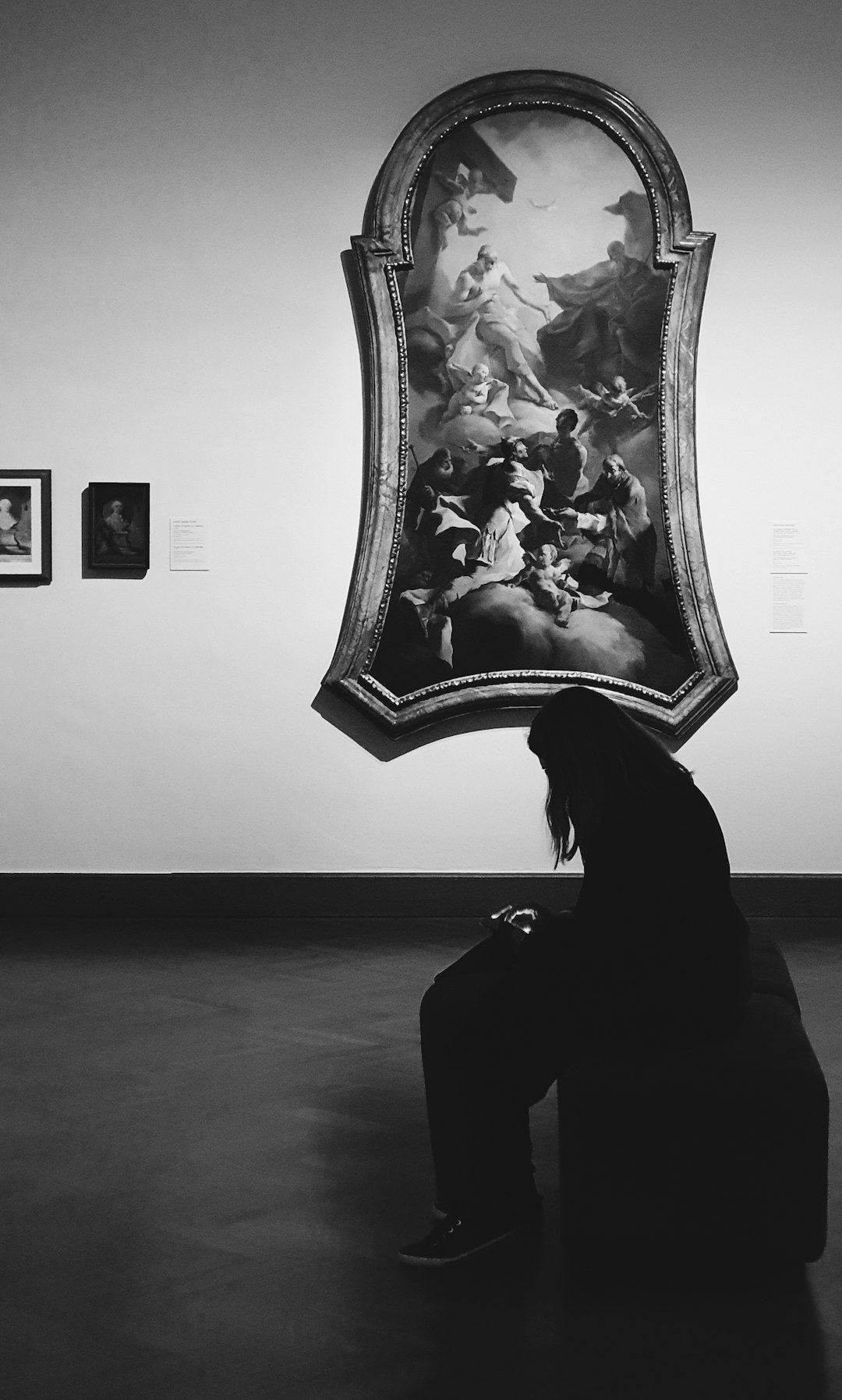 woman in black dress sitting on floor with white flower painting