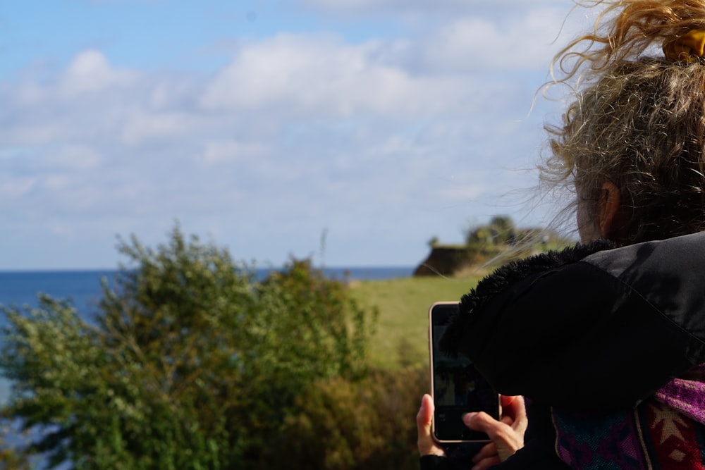 person taking photo of green grass field during daytime