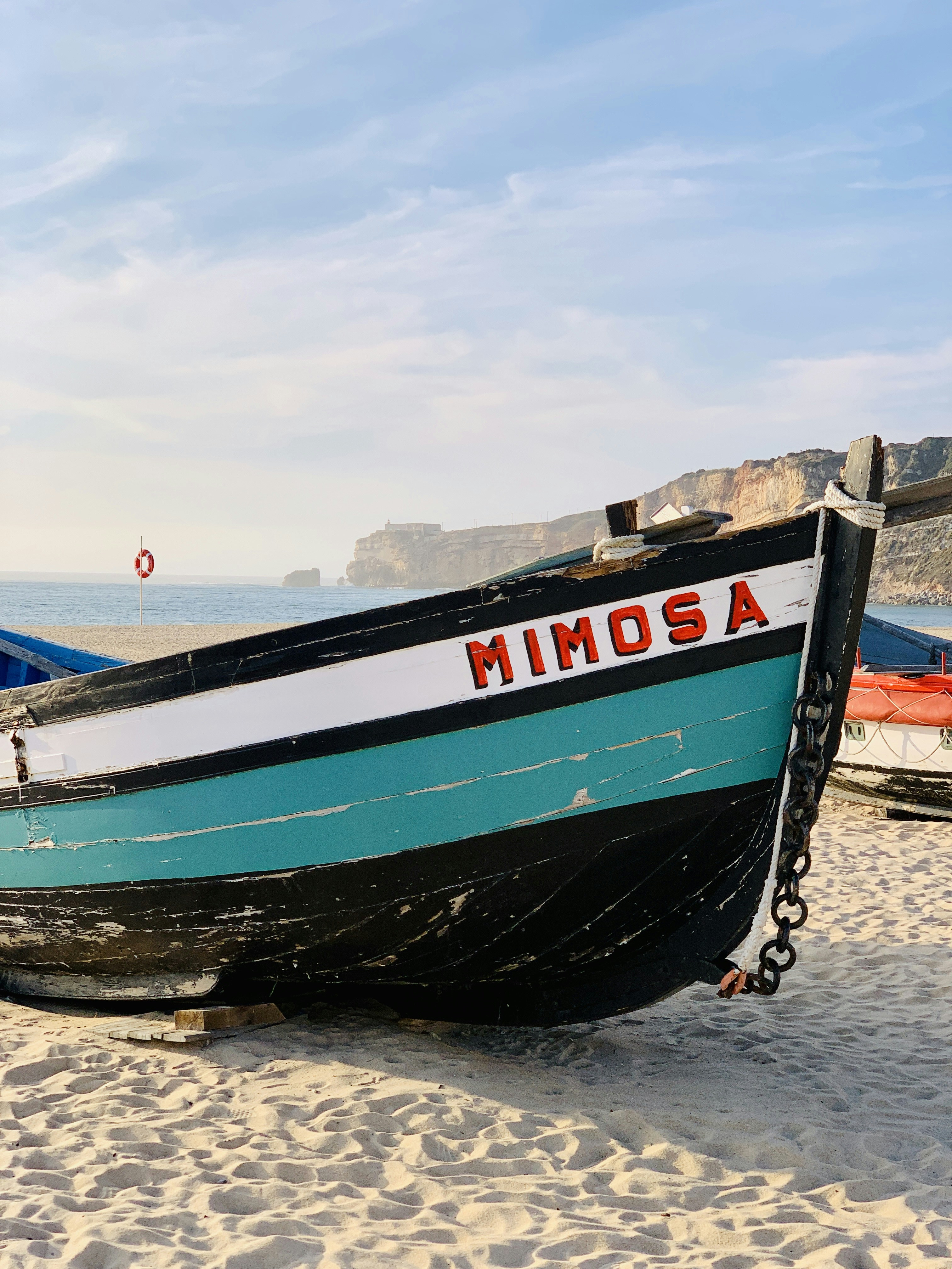 blue and white boat on brown sand during daytime