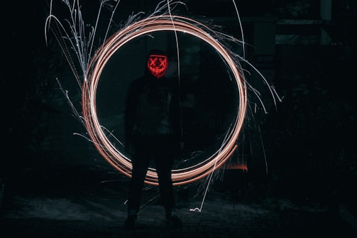 A mysterious anime character cloaked in shadows with glowing eyes.