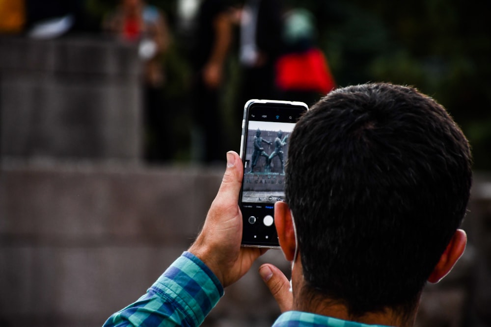 man in blue and white long sleeve shirt holding silver iphone 6