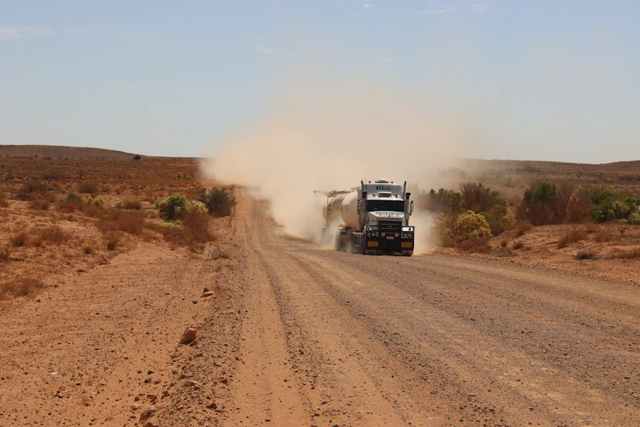 A road train raising dust on a red dirt road in outback Australia