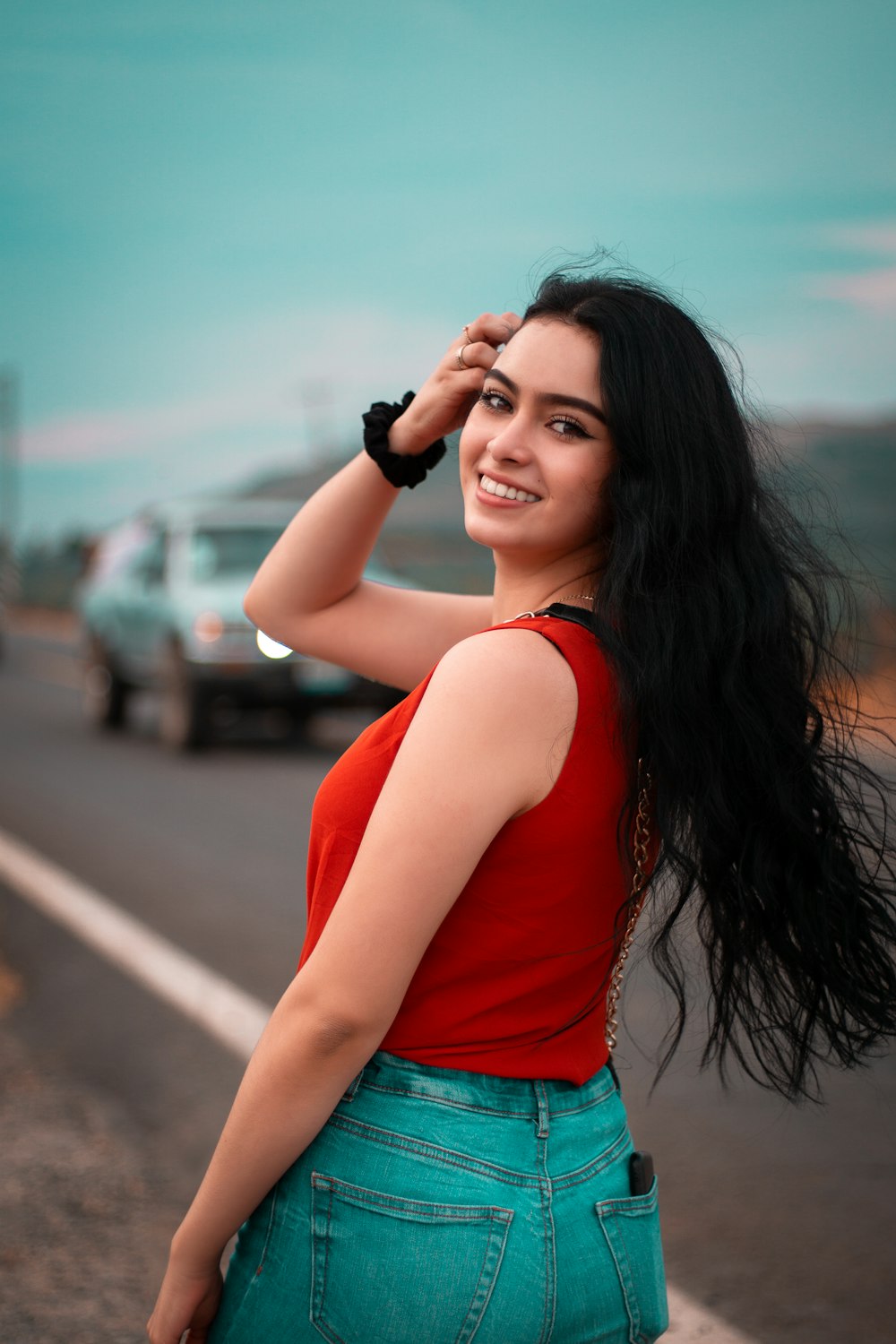 woman in red tank top and blue denim shorts holding black dslr camera