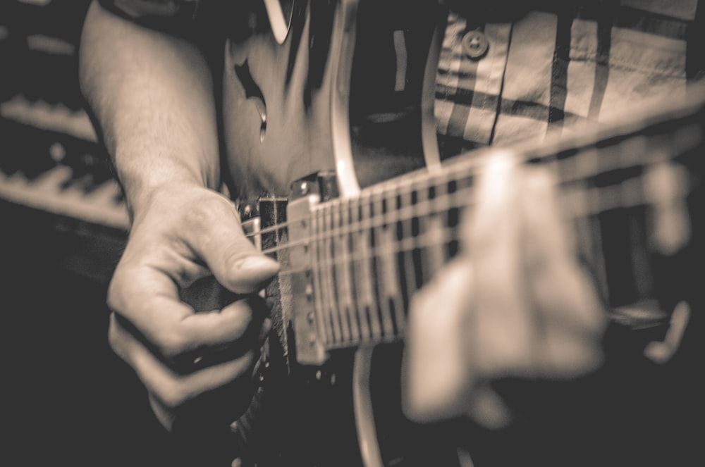 grayscale photo of person playing guitar