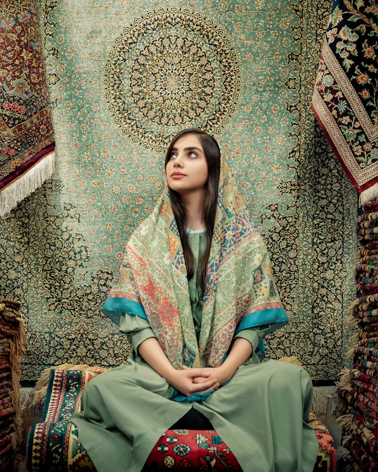 woman in blue and green dress sitting on brown and beige floral couch