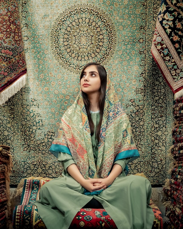 woman in blue and green dress sitting on brown and beige floral couch