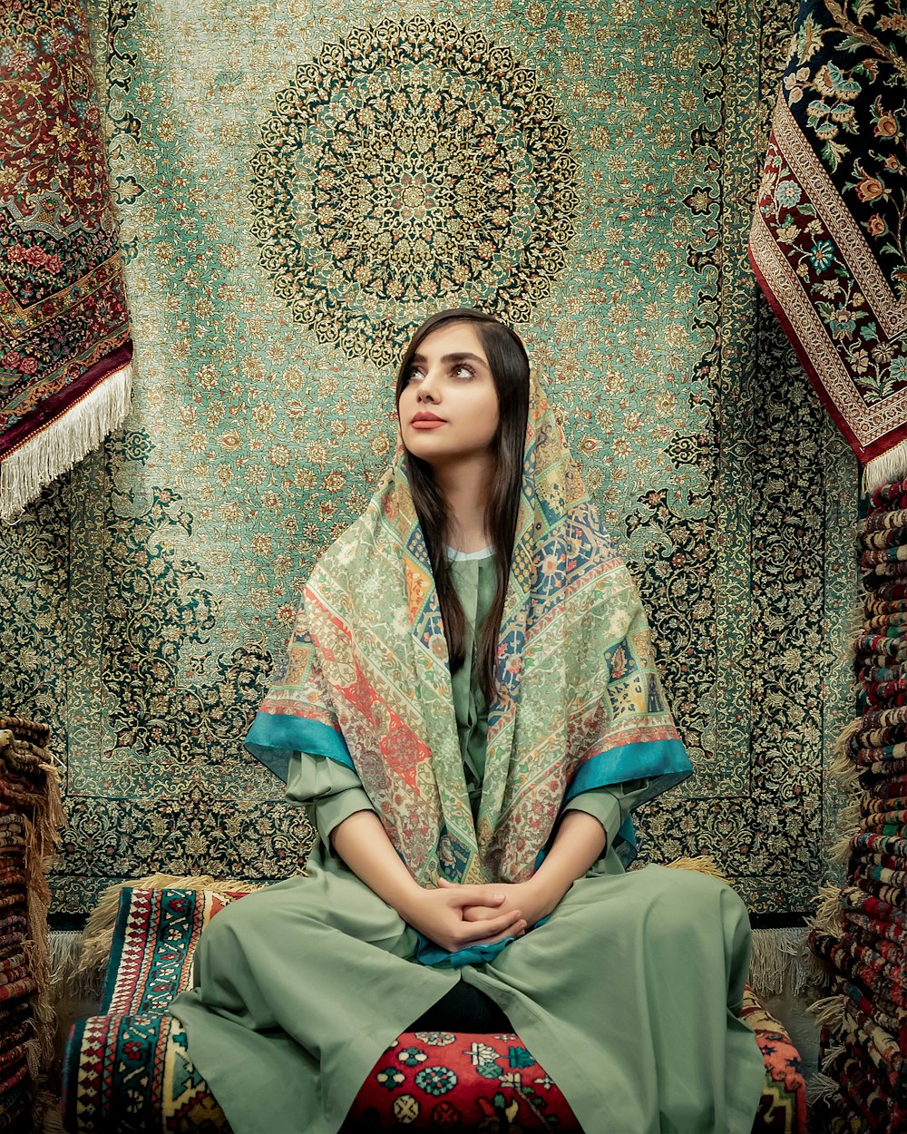 woman in blue and green dress sitting on brown and beige floral couch