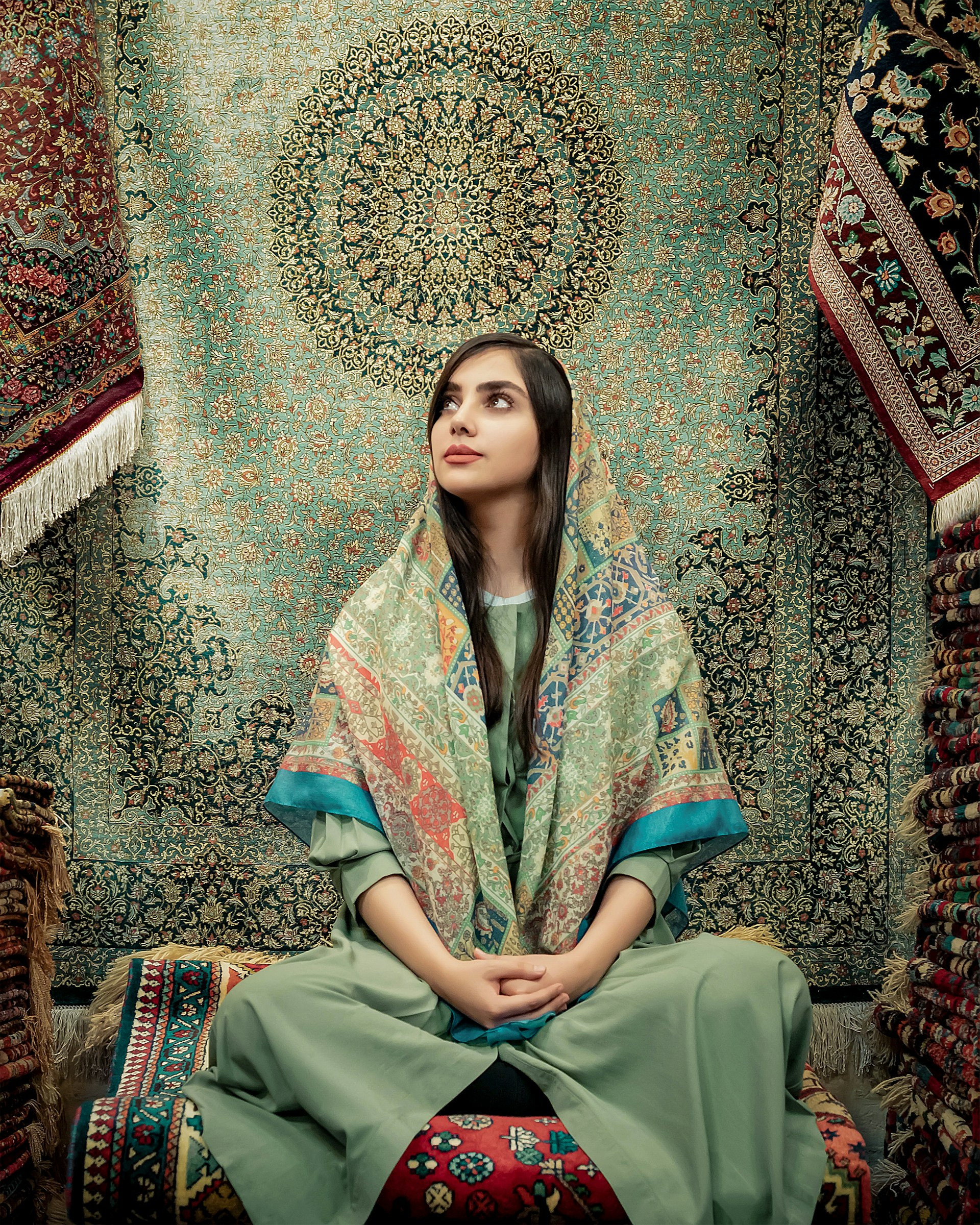 woman in blue and green dress sitting on brown and beige floral couch