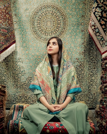 woman in blue and green dress sitting on brown and beige floral couch